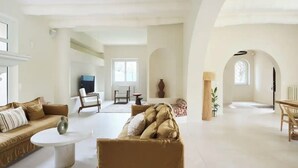 A spacious living room with a high ceiling, a fireplace, and a dining area with a table and chairs. - Villa El Sol Juan Les Pins (Antibes)