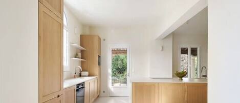 A modern kitchen with wooden cabinets, a central island, and a view to the outdoors.