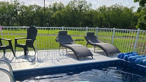 A swimming pool with lounge chairs and a floating mat.
