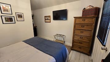 A bedroom with a bed, dresser, and wall-mounted TV.