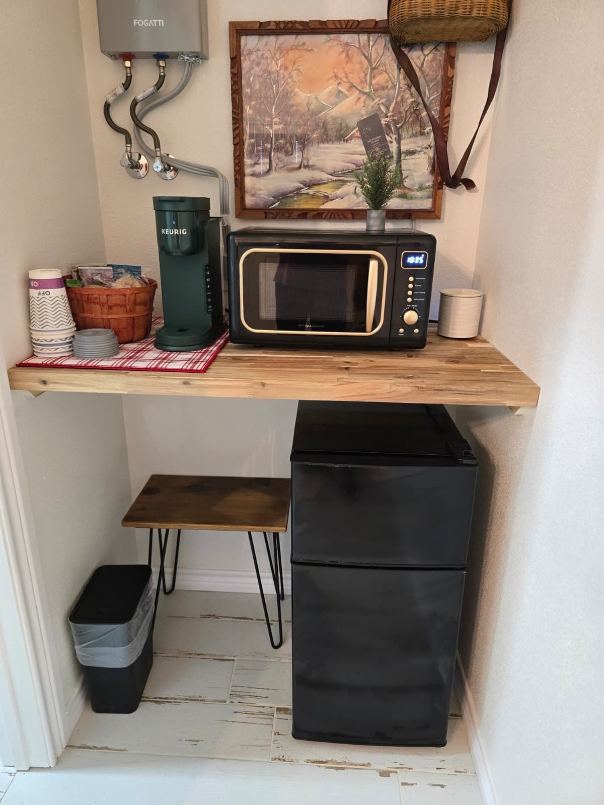 Una kitchenette compacta con microondas, cafetera y un refrigerador pequeño.