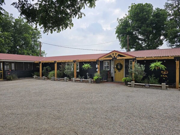 A building with a red roof, a welcome sign, and a gravel driveway.