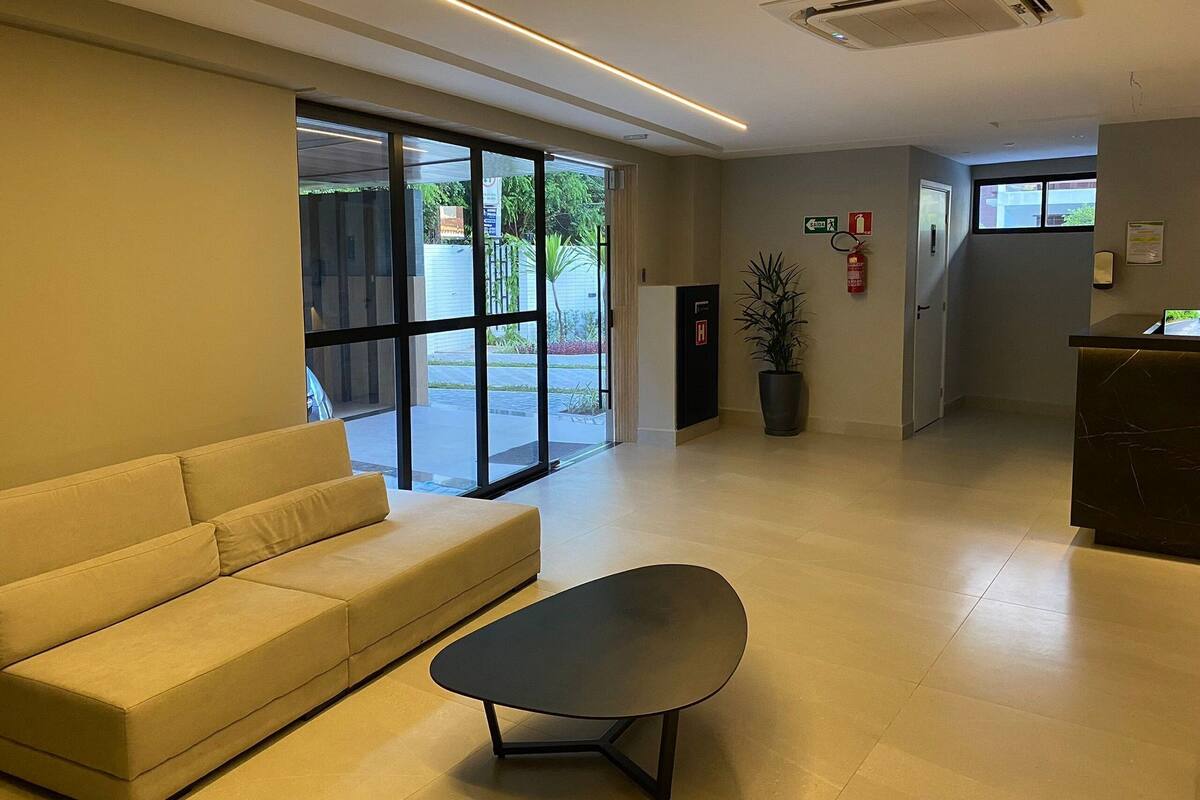 A modern lobby with a sofa, a table, a reception desk, and a fire extinguisher.