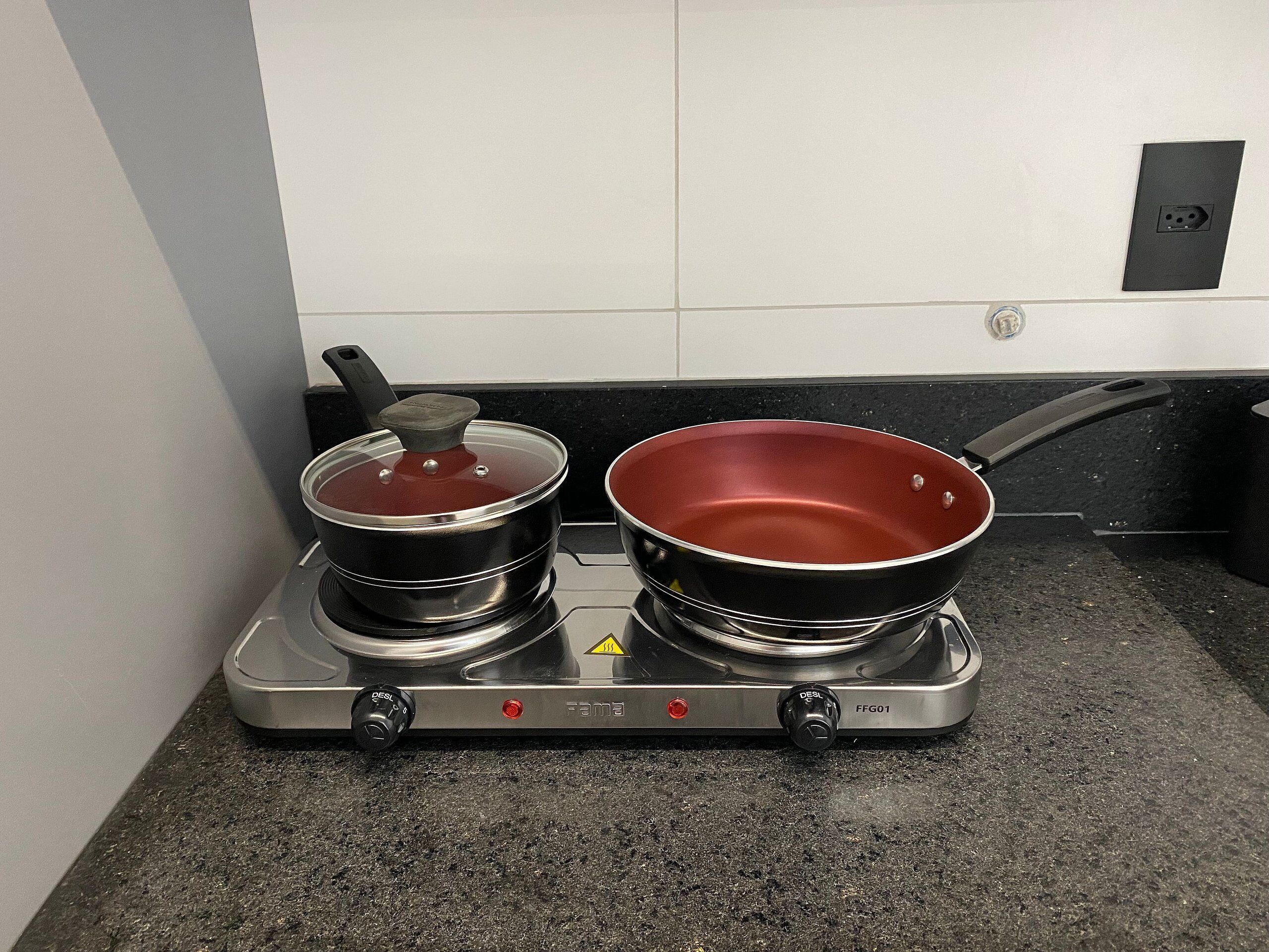 Une cuisine équipée d’une cuisinière à gaz, de deux casseroles et d’une poêle.