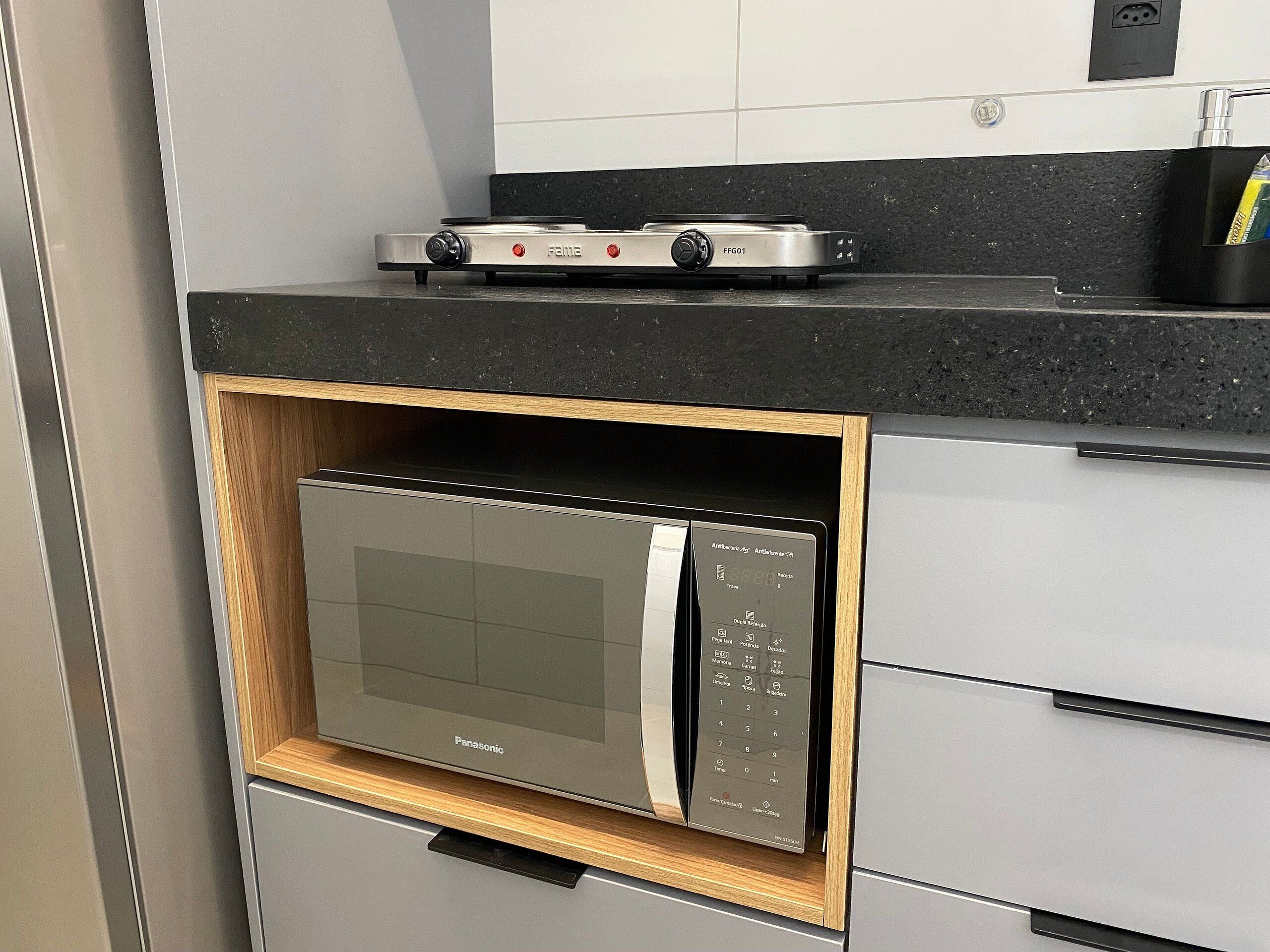 Uma cozinha com micro-ondas embutido, fogão a gás e armário de madeira.