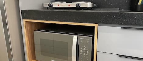 Uma cozinha com micro-ondas embutido, fogão a gás e armário de madeira.