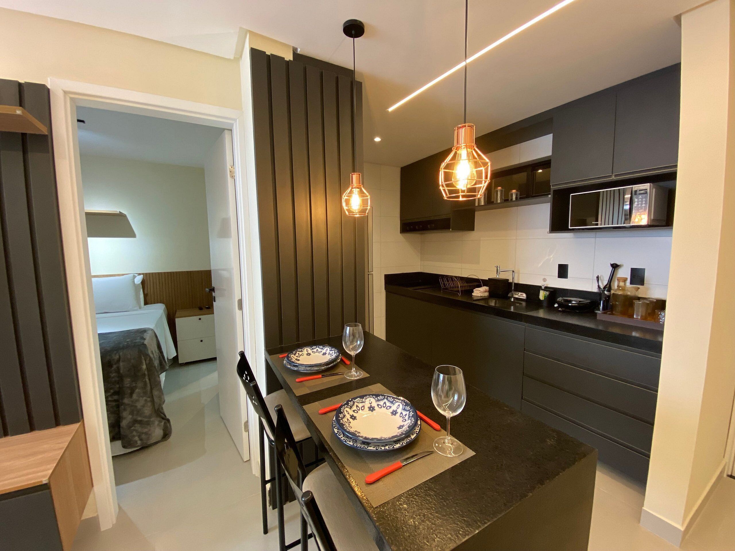 A modern kitchen with a central island, dark cabinetry, and pendant lighting.