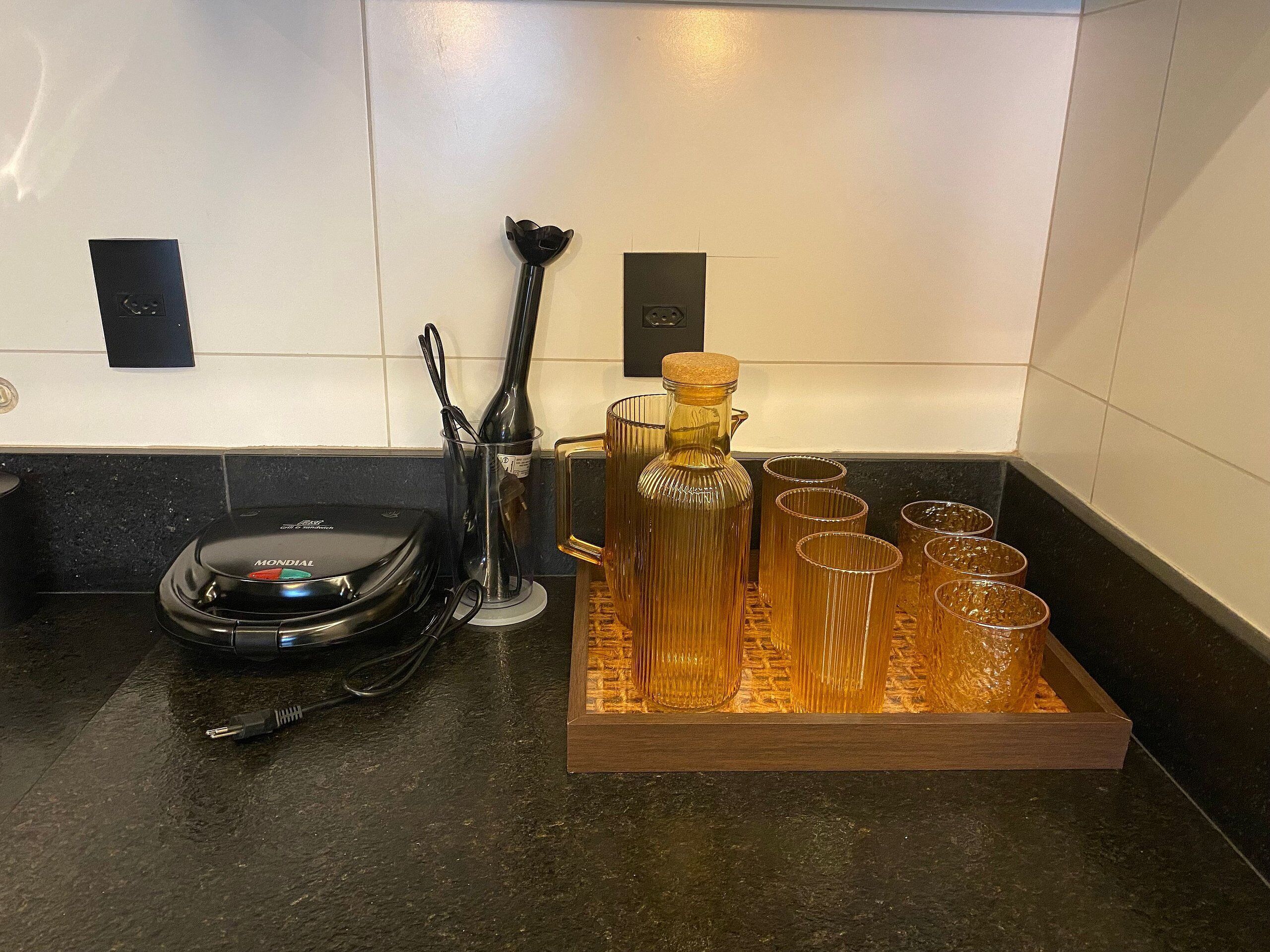 Eine Küchenarbeitsplatte mit einer Kaffeemaschine, einer Flasche und mehreren Gläsern.