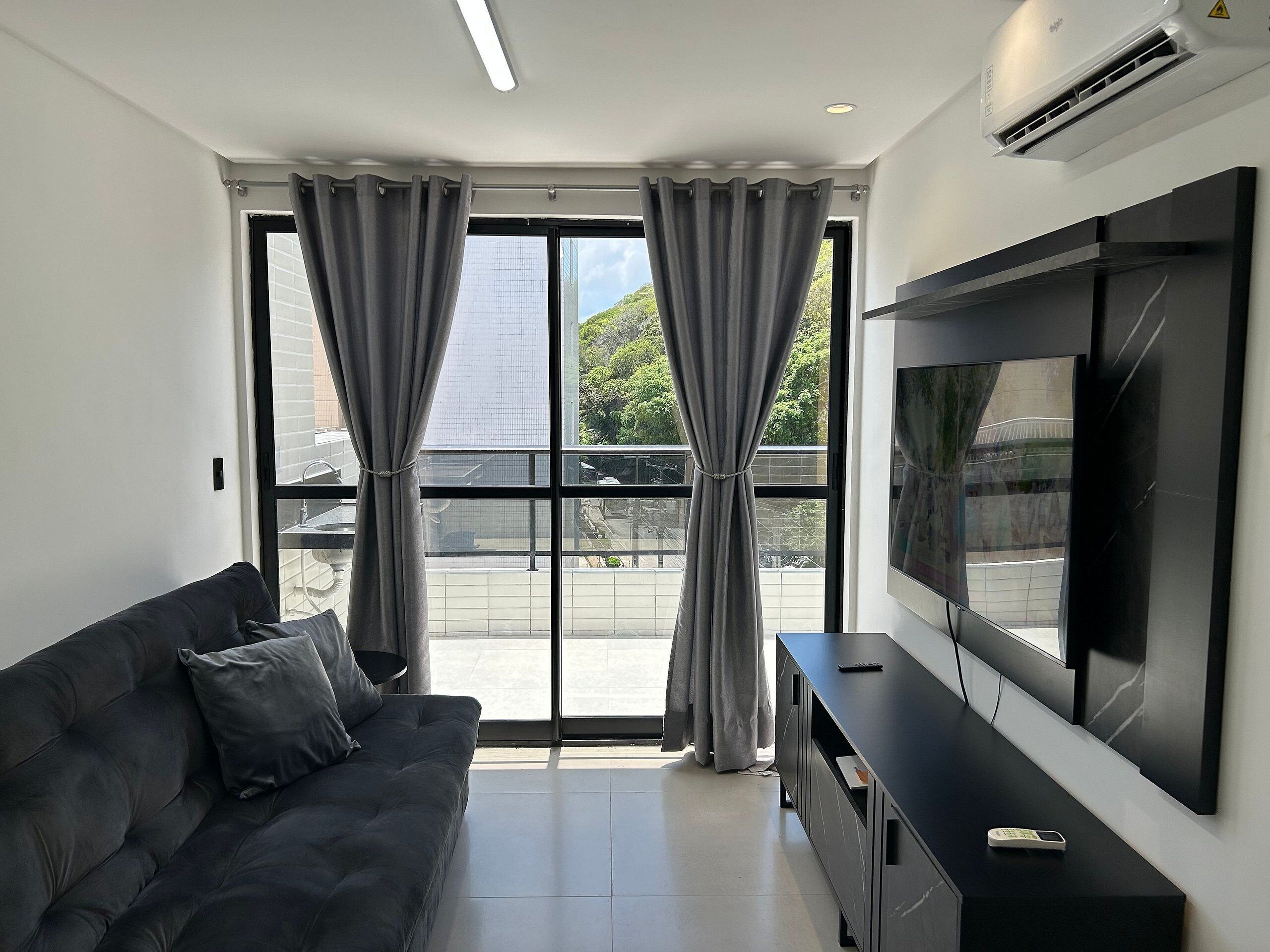 A modern living room with a sofa, TV, and a balcony view.