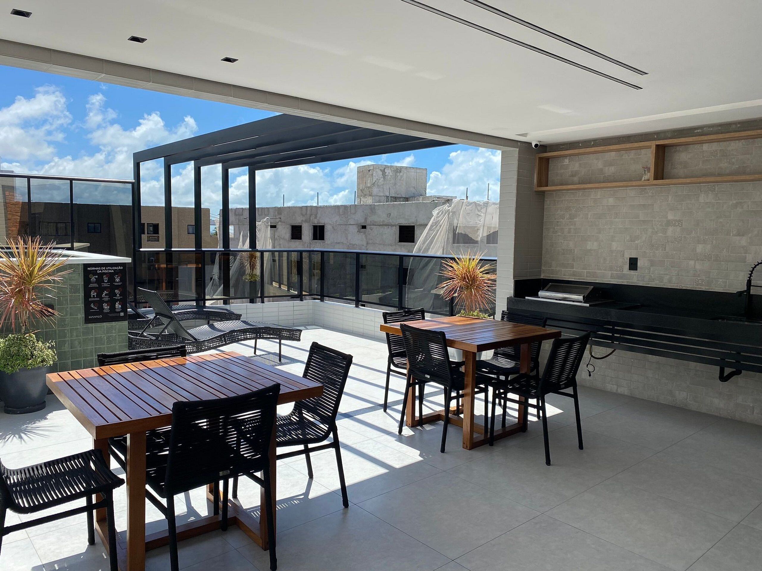 Una terraza en la azotea con una mesa de comedor, sillas y una zona de barbacoa.