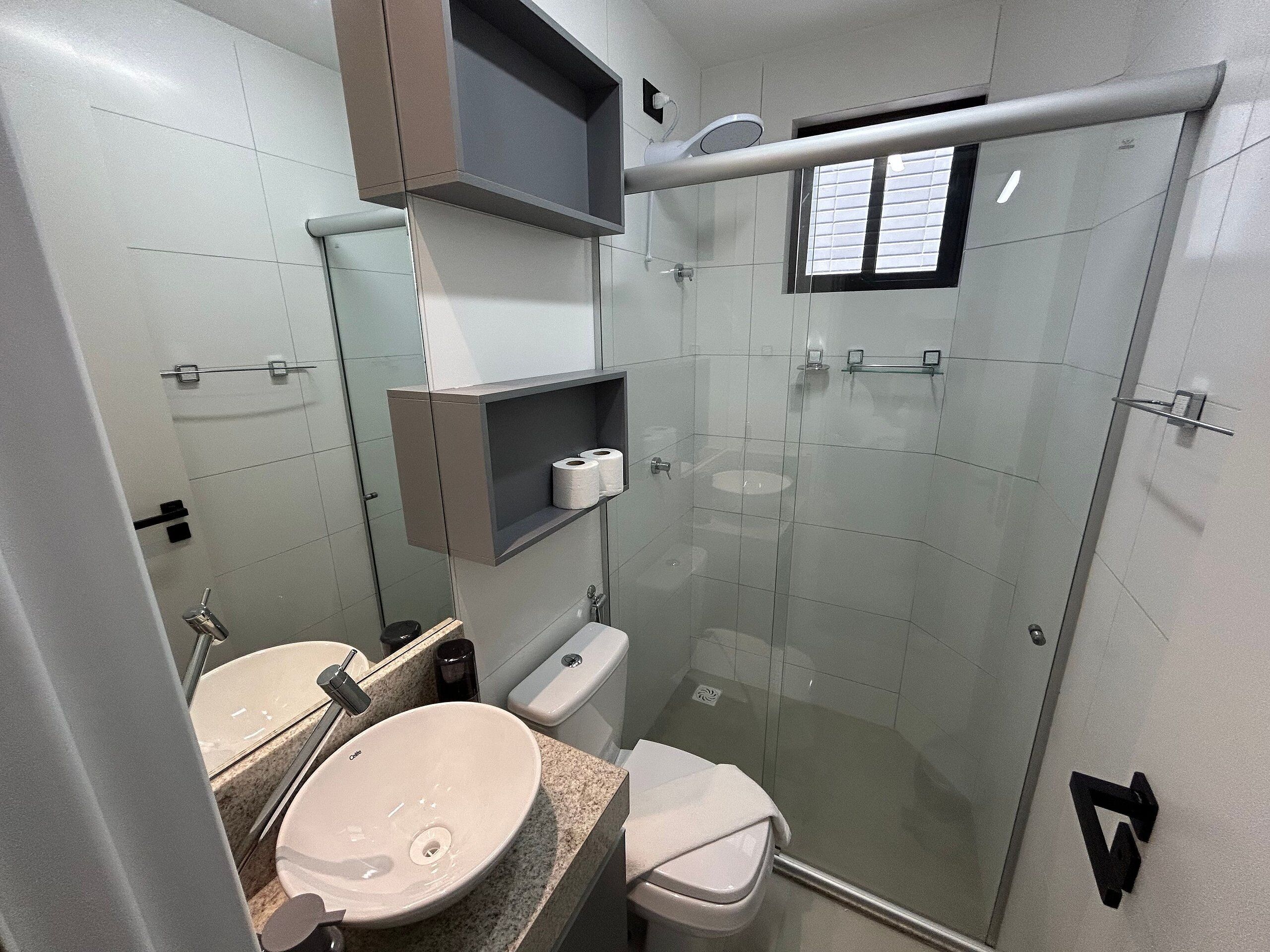 Ein modernes Badezimmer mit einer Duschkabine aus Glas, einem Waschbecken und einer Toilette.