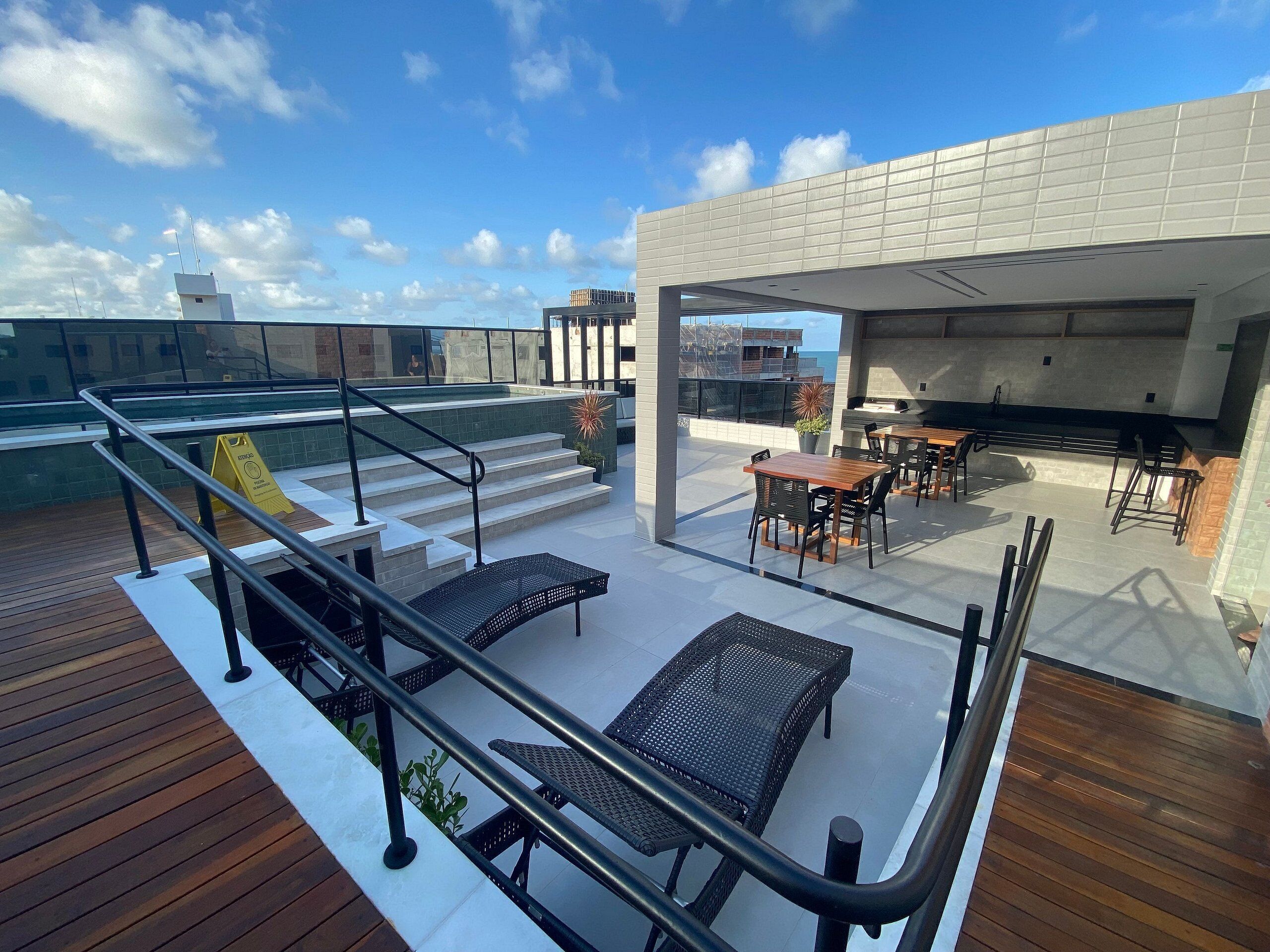 A rooftop terrace with outdoor seating, a staircase, and a view of the cityscape.