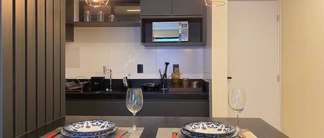 Una cocina moderna con una mesa de comedor, sillas y dos lámparas colgantes.