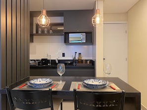 A modern kitchen with a dining table, chairs, and two pendant lights. - Bela Hospedagem - Mahalo Flats a 80m da praia (João Pessoa)