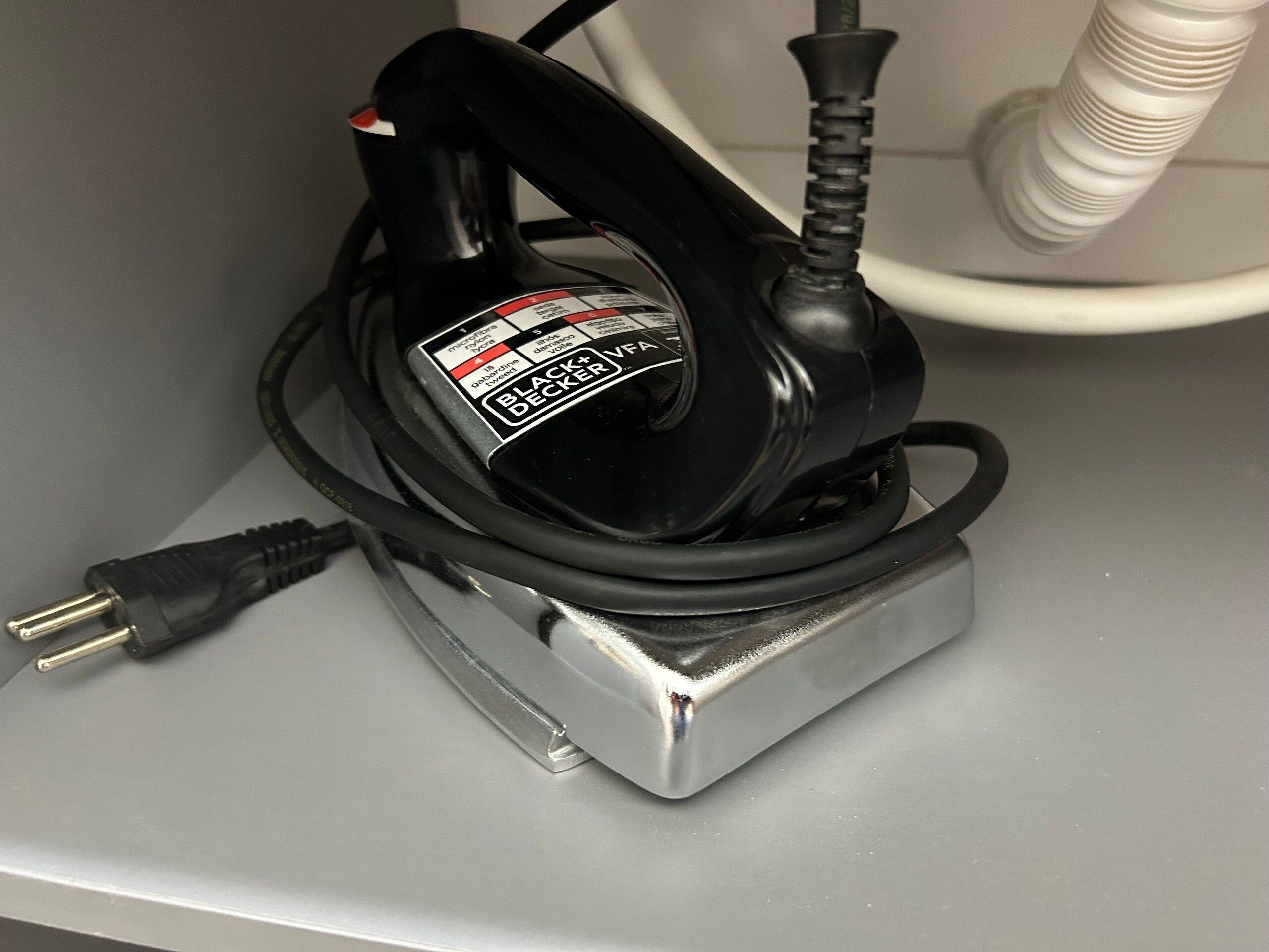 Un outil électrique de la marque Black+Decker, posé sur un support métallique, avec un câble d’alimentation branché.