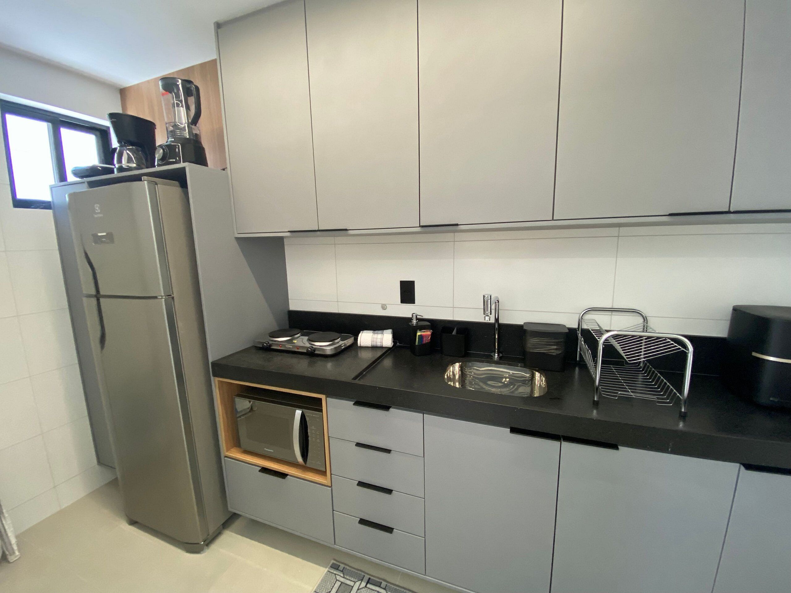 Eine moderne Küche mit Kühlschrank, Mikrowelle, Herd, Spüle und verschiedenen Küchenutensilien.