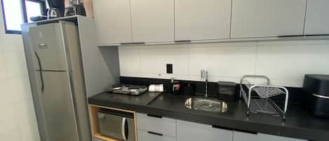 A modern kitchen with a refrigerator, microwave, stove, sink, and various kitchen utensils.