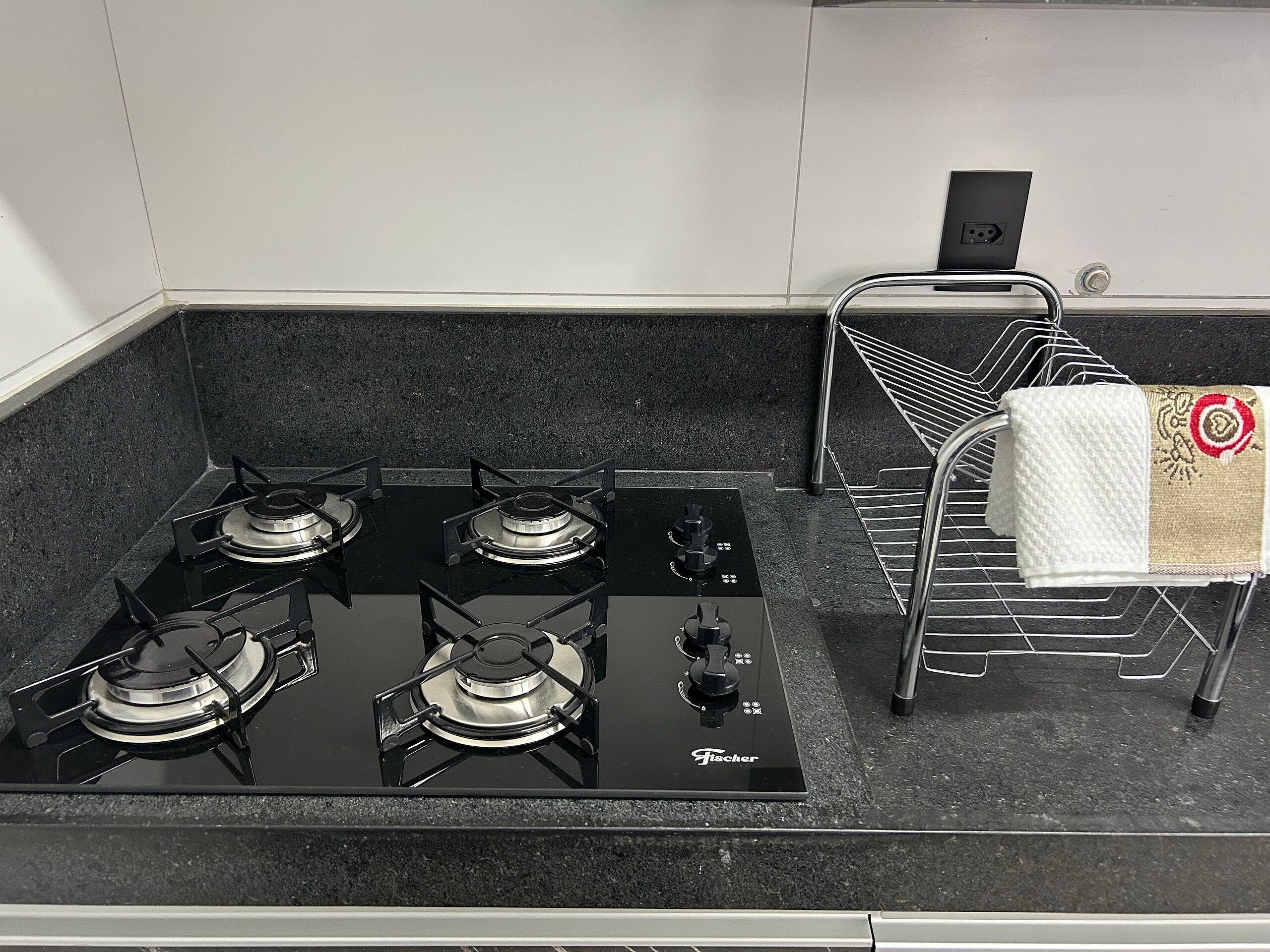 A kitchen with a black stove, a metal rack, and a towel.