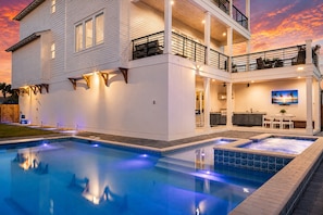 Una casa de dos pisos con piscina, mobiliario exterior y zona de cocina.