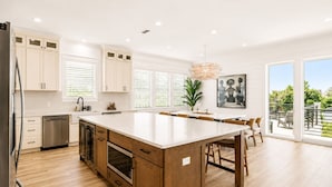 A modern kitchen with wooden cabinets, a large island, and a view to the outdoors. - Casa Blanca | Rooftop Bar • Elevator • Golf Cart • 400' Beach Access (Miramar Beach)