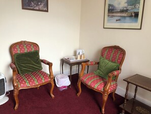 Two ornate chairs with patterned upholstery, a small table with a tray of items, and a framed picture on the wall. - The Great Western Hotel (Paignton)