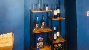 A room with a blue wall, a shelf with wine bottles, glasses, and a box labeled 'Happiness is homemade with love & butter'. - The Great Western Hotel (Paignton)
