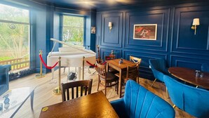 A room with a grand piano, wooden furniture, and blue walls. - The Great Western Hotel (Paignton)