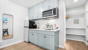 A modern kitchen with light blue cabinets, a stainless steel microwave, and a black refrigerator. - New Modern Apartment w/ AC - Central to SD (El Cajon)