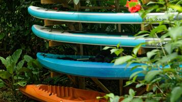 Un montón de kayaks sobre una plataforma de madera rodeada de vegetación.