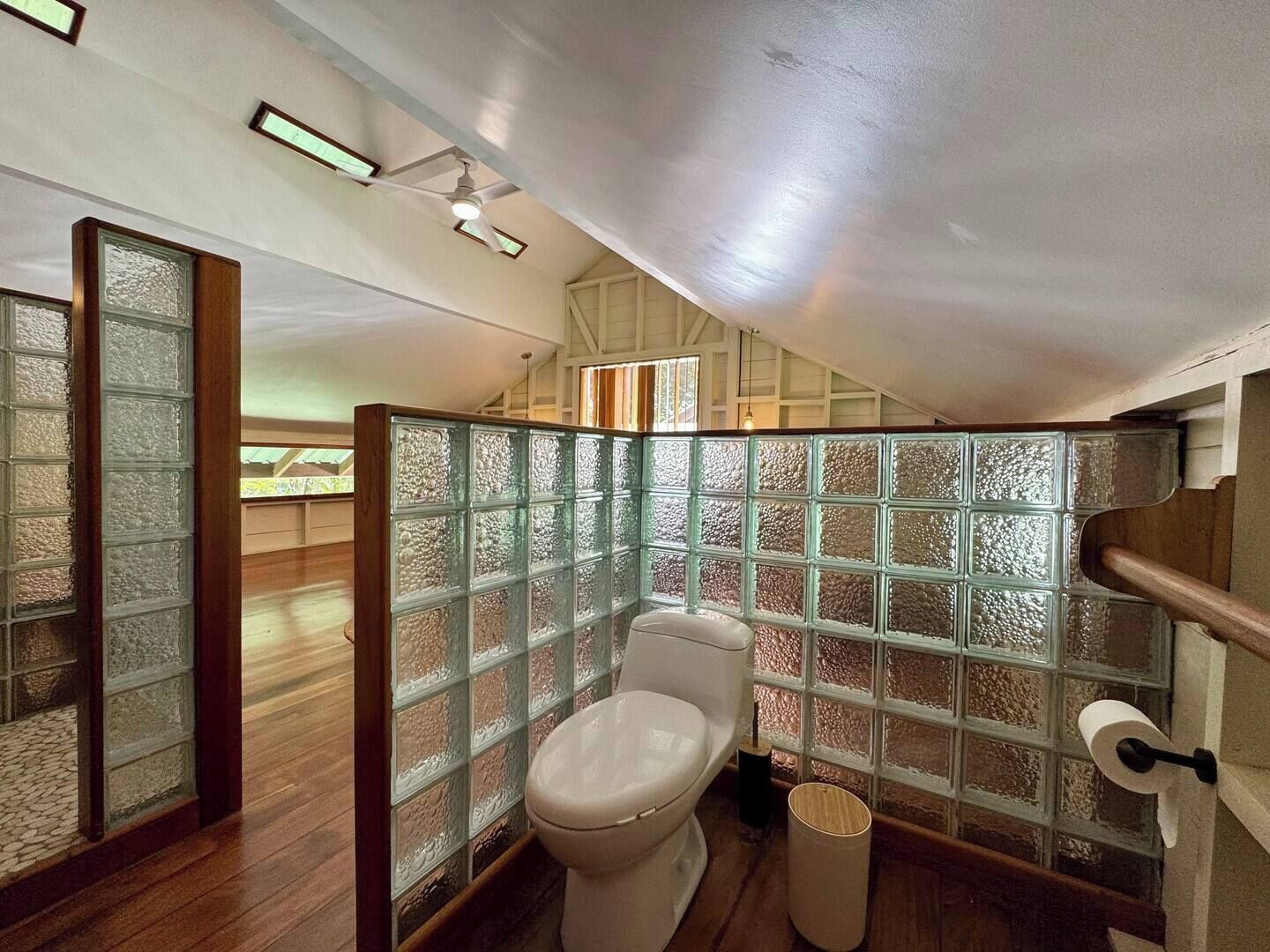 Un bagno piccolo e funzionale con il water, pavimento in legno e divisorio in vetro satinato.