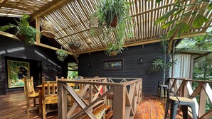 A wooden deck with a thatched roof, surrounded by indoor seating and hanging plants. - The Lodge at Punta Rica (Bastimentos)