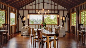 A spacious dining area with a high ceiling, wooden beams, and large windows offering a view of greenery. - The Lodge at Punta Rica (Bastimentos)