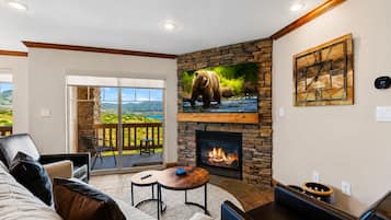 Una sala de estar con chimenea, un sofá, una mesa de centro y vistas al exterior a través de un ventanal.