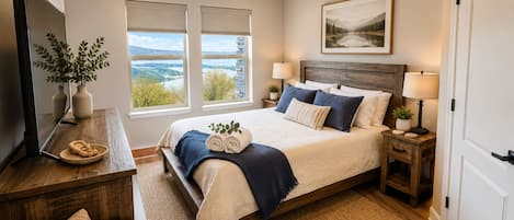 Un dormitorio con cama, mesitas de noche, televisor, ventana y vistas, además de una puerta.