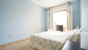 Un dormitorio con cama, ventana y vista al exterior.