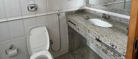 Une salle de bain avec des toilettes, un lavabo et une douche.