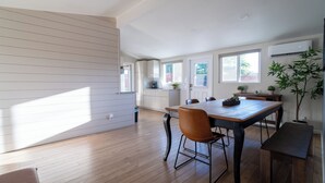 Een moderne keuken met witte kastjes, een eettafel met stoelen en een groot raam dat natuurlijk licht binnenlaat.
