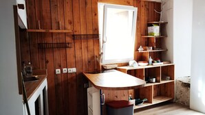 A compact kitchen with wooden walls, a window, and a sink.