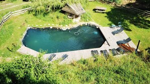 A rectangular swimming pool with a wooden deck and lounge chairs, surrounded by greenery and a small wooden structure. - Apartment-Comfort-Private Bathroom-Mountain view (Saint-Péray)