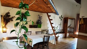A dining area with a wooden ceiling, a table set for four, and potted plants.