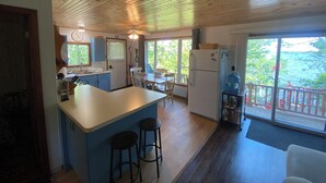 Une cuisine dotée d’un îlot central, de tabourets de bar, d’un réfrigérateur et d’un coin repas avec une table et des chaises.