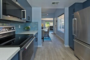 Una cucina moderna con elettrodomestici in acciaio inossidabile, zoccolo a mosaico e pavimento in legno.