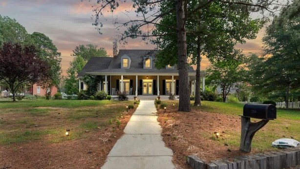 A two-story house with a front porch, a mailbox, and a pathway leading to the entrance. - 20 Acre Retreat Near Apex-Rentable Event Venue (New Hill)