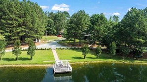 A lake with a dock, surrounded by trees and a grassy area. - 20 Acre Retreat Near Apex-Rentable Event Venue (New Hill)