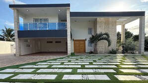 Una casa moderna de dos pisos con entrada pavimentada y jardín ajardinado.