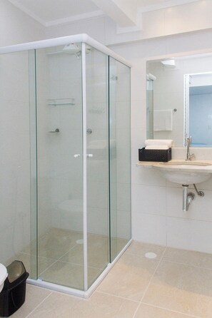 Une salle de bain moderne avec une douche à parois de verre, un lavabo avec un miroir et un sol carrelé.