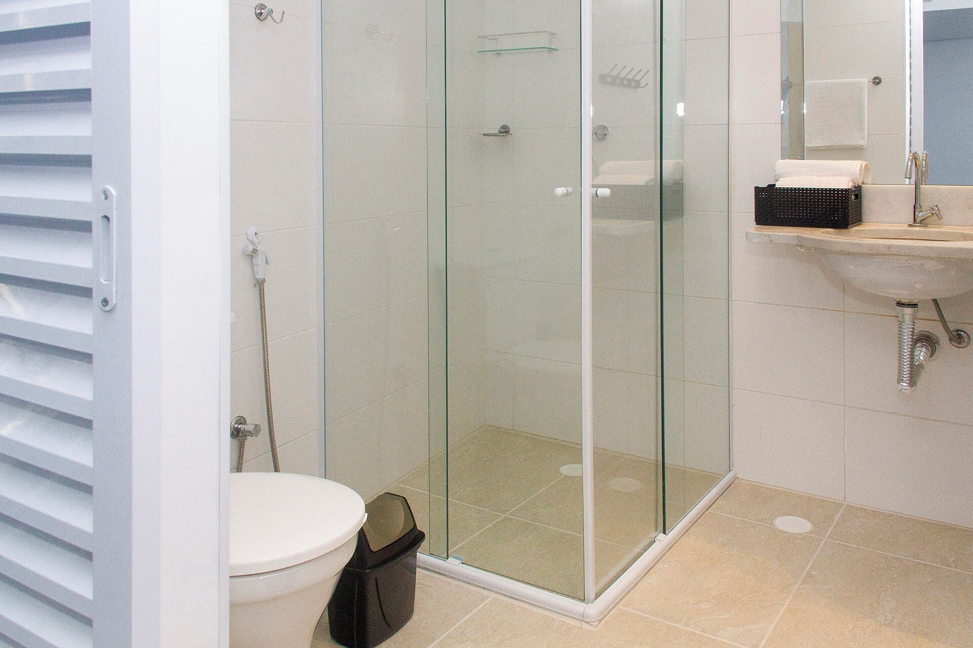 A bathroom with a glass-enclosed shower, a toilet, and a sink with a mirror.