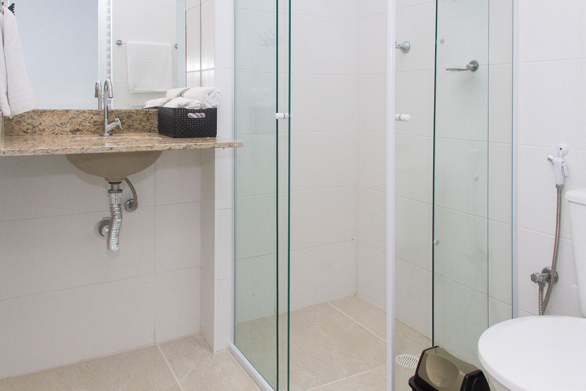 Un baño moderno con ducha envuelta en vidrio, lavamanos con encimera de mármol y retrete.