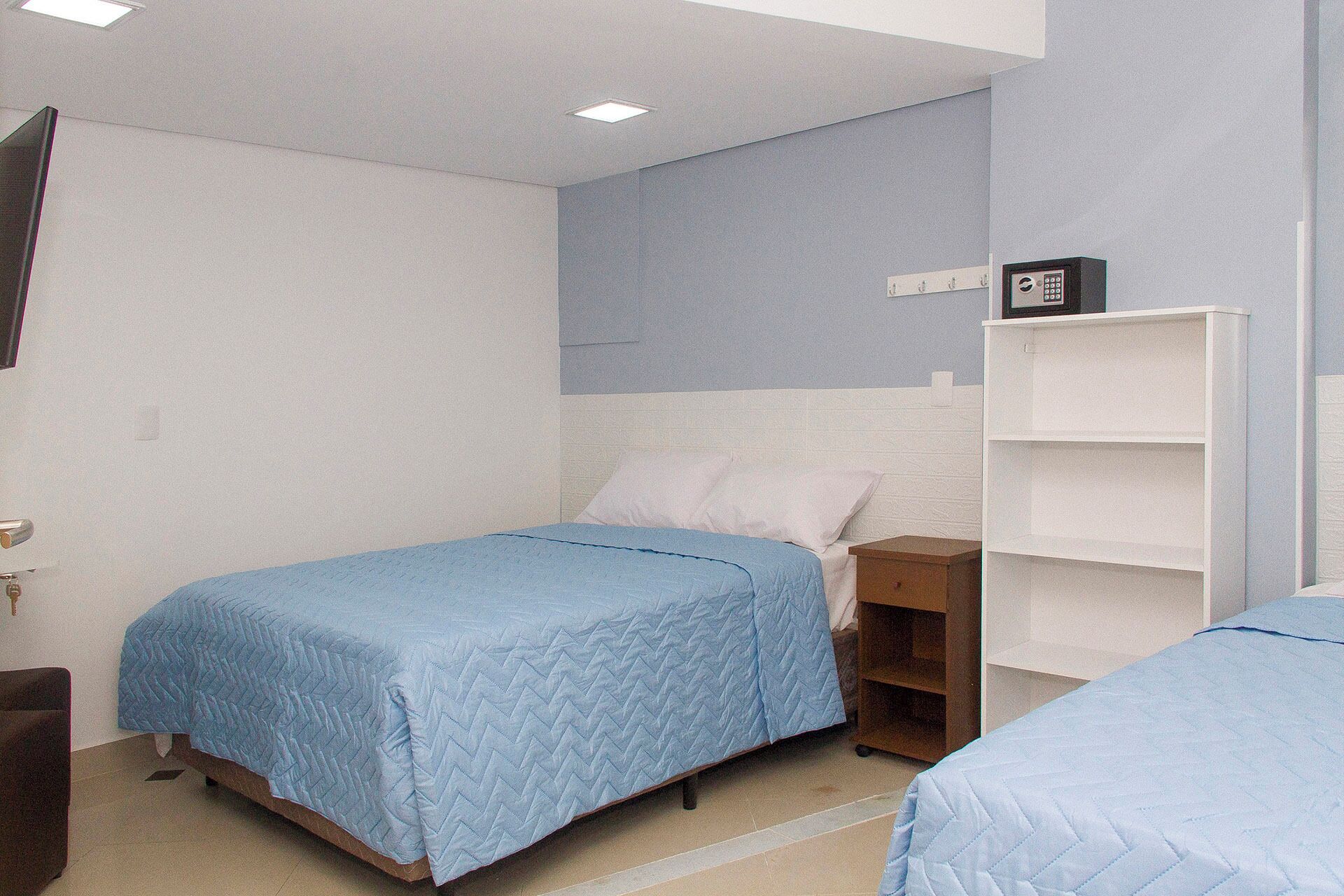 Un dormitorio con dos camas individuales, un armario blanco y un escritorio pequeño.