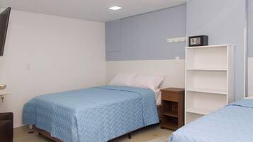 Un dormitorio con dos camas individuales, un armario blanco y un escritorio pequeño.